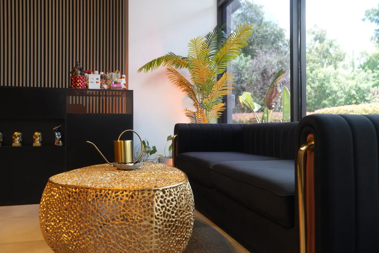 The lounge: a black sofa and a gold drum table by the window